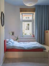 A red platform bed in one of the kids’ rooms features built-in cabinets.