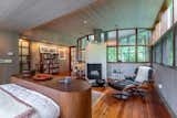 Curved walls of glass continue into the primary bedroom, which has an angular woodburning fireplace.