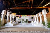 A mockup model of Lauren Halsey’s public sculpture park in Los Angeles, CA, with concrete-block planters, tall white columns with Egyptian motifs, sculptures of sphynxes, and large white concrete cube with a corner shaved away to provide entry into its interior that will act as a community space for Summaeverythang, her nonprofit organization is displayed in a warehouse.