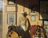 A cowgirl mannequin with a white hat and sequin clothing stands beside saddles and old posters and photos of cowboys and rodeos in a museum in Cheyenne, Wyoming.