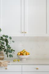 Concrete Collaborative Extra Small Marble Chip Pacifica slabs in ivory on the kitchen countertops are paired with the brand’s Dwell x Strands collection on the backsplash in the Stringer pattern with a Beige color accent. The hexagonal tiles add a subtle geometric playfulness.