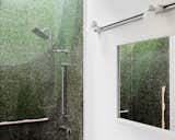 The shower's verdant green tiling, natural light, and organically shaped grab bars bring an outdoor feeling inside.