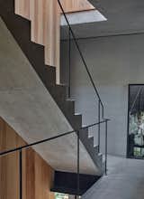 The stairs connecting the three levels of the house are made of concrete, with iron railing. “The are no white walls in the house; everything is either paneled in pine wood or or converted in a stucco that mimics the look of concrete,” says the architect.