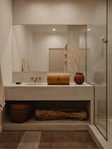 An antique wicker chest sits beside a ceramic vessel by Kevin Willis in the bathroom.