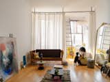 Phoenix plays with the family dog next to a vintage J-149 sofa by Erik Ole Jørgensen in the living area. The couple’s full-size bed is tucked behind semi-sheer curtains in the corner.