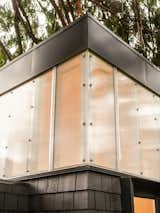 Clerestory polycarbonate panels wrap around detached work shed office clad in black shingles and blackened metal by Linework Architecture in backyard of home in Seattle, Washington.