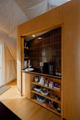White oak millwork unit with rounded corners housing kitchenette lined with black porcelain tile in a geodesic dome by FDomes with an interior designed and built by SpotLab in Lost Woods glamping site situated in Boyne Falls, Northern Michigan.