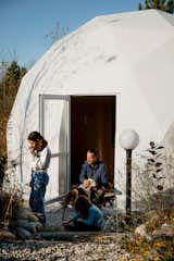 Family plays with dog in doorway of a geodesic dome by FDomes with an interior designed and built by SpotLab in Lost Woods glamping site situated in Boyne Falls, Northern Michigan.