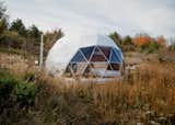 Bedroom seen through triangular glass panels of geodesic dome by FDomes with an interior designed and built by SpotLab in Lost Woods glamping forested site situated in Boyne Falls, Northern Michigan.