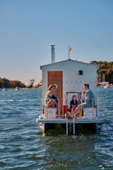 Family lounge on the bow of a floating sauna clad in red-and-white wood slats designed and built by Peter Boldt sailing off the coast of Cos Cob, Connecticut.