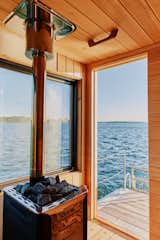 Wood-burning stove filled with rocks sits in floating sauna clad in red-and-white wood slats designed and built by Peter Boldt as it sails off the coast of Cos Cob, Connecticut.