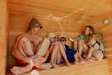 Family sits in floating sauna clad in red-and-white wood slats designed and built by Peter Boldt as it sails off the coast of Cos Cob, Connecticut.
