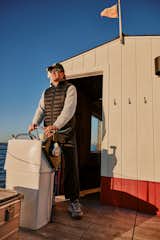 Man sails floating sauna clad in red-and-white wood slats designed and built by Peter Boldt off the coast of Cos Cob, Connecticut.