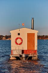 Floating sauna clad in red-and-white wood slats designed and built by Peter Boldt sails off the coast of Cos Cob, Connecticut.
