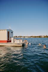 Family swims in ocean around floating sauna clad in red-and-white wood slats designed and built by Peter Boldt off the coast of Cos Cob, Connecticut.