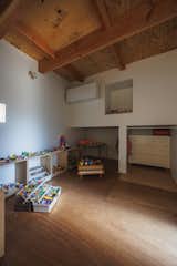 Attic playroom with exposed wood ceiling beams and panels, white walls, plywood storage unit with cubbyholes housing Legos, and nooks with dresser and low round wooden table in the Hirano, Osaka, Japan home of Tsuyoshi and Maya Ohama designed by local firm FujiwaraMuro Architects.