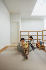 Mother reads with her two children in playroom with cushioned flooring and white walls in the topmost story of the Hirano, Osaka, Japan home of Tsuyoshi and Maya Ohama designed by local firm FujiwaraMuro Architects.