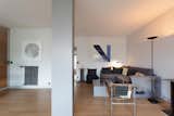 Livingroom in an apartment in the prototypical urban residential apartment building the Immeuble Clarté in 1932, a now UNESCO World Heritage site in Geneva, Switzerland commissioned by Edmond Wanner and designed by Le Corbusier and his cousin Pierre Jeanneret with white walls, sectional purple grey sofa, metal armchair, metal geometric coffee table, tall black floor lamp, and contemporary geometric artwork.