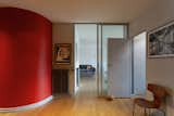 Entryway into an apartment in the prototypical urban residential apartment building the Immeuble Clarté in 1932, a now UNESCO World Heritage site in Geneva, Switzerland commissioned by Edmond Wanner and designed by Le Corbusier and his cousin Pierre Jeanneret with translucent floor-to-ceiling glass doorways and curving wall painted bright red.