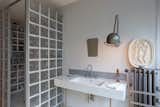 Bathroom of an apartment in the prototypical urban residential apartment building the Immeuble Clarté in 1932, a now UNESCO World Heritage site in Geneva, Switzerland commissioned by Edmond Wanner and designed by Le Corbusier and his cousin Pierre Jeanneret with shower enclosed by glass blocks, wall-mounted sink, and wall-mounted brushed-metal lamp light sconce.