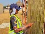 A thatched covering is applied to bamboo panels before adding a coat of lime plaster.