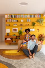 Nicholas Beggs and Joyce Prestes in the living area of their new home in São Paulo. The ’70s property was redesigned by Arkitito. The rug on the floor, by Rodrigo Ohtake, complements the bright yellow wall in the background.