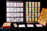 On the left, a set of playing cards designed by French artist Yannick Pennanguer in 1989 features images of musicians like Thelonius Monk and Billie Holiday. On the right, a set of 19-century French playing cards that are actually tiles sit next to the brass plates for a set of playing cards designed in 1915 by Armand-Gustave Houbigant, the son of a royal perfumer. 