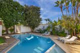 The lush backyard features tropical plants and a V-shaped pool.