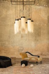 The circles on the gallery’s wall indicate areas of repair, where small hand-cut stones were used to fill in the gaps between large stones and left exposed. An oversize pendant designed by Angela hangs from the ceiling. It’s made of fibers from the sansevieria (snake) plant that were tinted with a natural dye from a local tree.