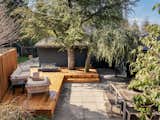 The backyard deck, which wraps around two conifers, is warmed by a gas fireplace.