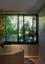 The bathroom features a concrete soaking tub, terrazzo flooring, and wood accents.