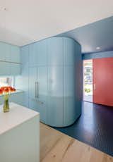The red-tiled entrance leads past a set of curvaceous powder-blue cabinets to the kitchen.