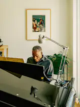 Charles plays piano in front of Before the First Whistle, a 1973 work by Romare Bearden.