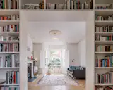 The proscenium bookshelves create a subtle divide between the living room and library, doubling as both a functional storage space and a showcase for the family’s extensive book collection.