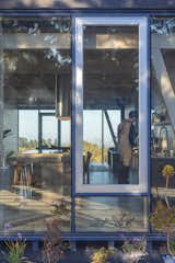 The central nave of the house is flanked by floor-to-ceiling windows, with ocean views to the west, and forest views to the east.