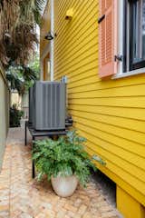 "Outside, we tucked the condensers away on black metal stands and surrounded them with a lovely gate, brickwork, tile, and lush plants to blend them seamlessly into the landscaping," says Dabito. The home’s exterior features Butterfield by Sherwin-Williams, with the shutters adding a playful contrast in Stone Fruit, also by Sherwin Williams.