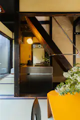 A tiny kitchen is tucked beneath the original wood staircase, which was previously hidden behind sliding doors. It’s lit by a Gregg lamp from Foscarini.