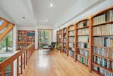 The library overlooks the living room, receiving natural light from the large angled windows.