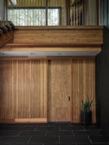 The ground-floor entryway is wrapped in warm, natural materials that echo the palette of the surrounding forest. A mudroom, hidden behind the sliding door, keeps the mess of outdoor activities contained for the active family of five.