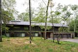 The bedrooms are tucked into the stone-clad lower level, while the upper floor, wrapped in Marvin Ultimate windows, opens up to the canopy. The planted roof insulates the lower level while helping the home recede into the landscape.