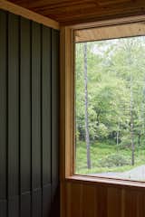 At the top of the stair hall, a generous custom Marvin window frames views of the forest beyond, inviting light deep into the home. The black-stained vertical timber panelling contrasts with the warmth of the Douglas fir, while the wood frame of the Marvin Ultimate collection echoes the forested landscape.