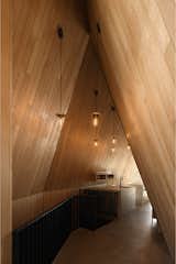 Steel handrails and dark kitchen fixtures contrast white oak walls, all selected for how they’ll wear in. “It’s similar to the weathering steel on the entry deck or the hemlock,” Braithwaite explains. “These are materials that age gracefully and develop character.”  Photo 18 of 23 in This Clever Twist on an A-Frame Cabin? It Started in a Classroom from This Clever Twist On an A-Frame Cabin? It Started in a Classroom