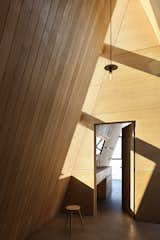 A vertical strip of windows at the building’s center, where the floor plan breaks, casts a warm glow onto the white oak walls.  Photo 21 of 24 in This Clever Twist on an A-Frame Cabin? It Started in a Classroom from This Clever Twist On an A-Frame Cabin? It Started in a Classroom