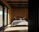 The primary bedroom features more white oak slats and sconces made by Braithwaite’s team.  Photo 22 of 24 in This Clever Twist on an A-Frame Cabin? It Started in a Classroom