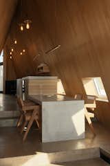 A concrete dining table with a waterfall edge extends from the kitchen.  Photo 16 of 23 in This Clever Twist on an A-Frame Cabin? It Started in a Classroom from This Clever Twist On an A-Frame Cabin? It Started in a Classroom