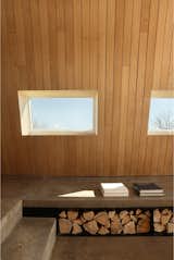 Firewood storage beneath a built-in concrete bench is both functional and aesthetic, complementing the rough-and-tumble energy and environment of Terence Bay.  Photo 19 of 23 in This Clever Twist on an A-Frame Cabin? It Started in a Classroom