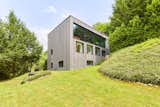 Set near a stream on a grassy hillside, this glass and timber home received the Bauhärepräis for architecture in 2020.
