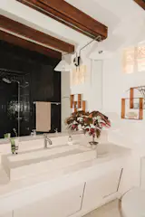 In another bathroom, a light-toned vanity contrasts with a black-tiled shower.