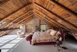 The top-floor primary suite sits just below the roof and its exposed wooden rafters.