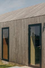 The black aluminum Senior Architectural Systems windows open flat to the Siberian larch exterior of the house. Guttering above the exterior walls is neatly concealed at the roof line.